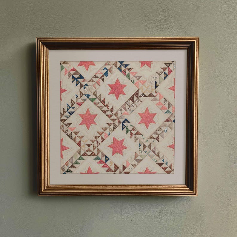May include: Framed quilt art featuring a star pattern in pink and various muted colors. The quilt is framed in a gold-colored wooden frame. The quilt design includes pink stars and geometric shapes.