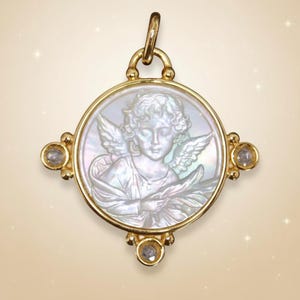 May include: A gold-toned pendant with a circular, mother-of-pearl cameo featuring an angel. The pendant has four decorative accents with clear gemstones. The angel has detailed wings and holds an object. The pendant is suspended from a gold bail.