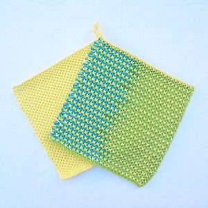 Puede incluir: Dos agarraderas de olla de ganchillo, una amarilla y otra con un patrón diagonal verde y azul.