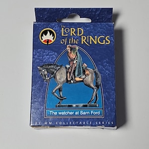 May include: A collectible figurine of a rider on horseback from "The Lord of the Rings" series. The box is blue with the title and a graphic of the rider. The text "The watcher at Sarn Ford" is displayed below the image.