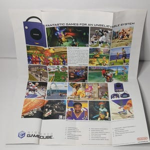 May include: A promotional Nintendo GameCube poster featuring the text "FANTASTIC GAMES FOR AN UNBELIEVABLE SYSTEM" at the top. The poster displays a grid of various video game screenshots, a purple GameCube console, and a list of game titles.