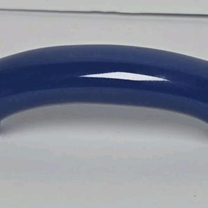 May include: A solid navy blue cabinet handle with a smooth, glossy finish and a curved, arch-shaped design. The handle features two circular mounting points at each end, providing a clean and simple look for furniture or cabinetry hardware.
