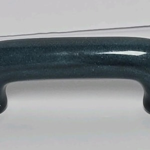 May include: A dark blue, arch-shaped cabinet handle with a smooth, glossy finish. The handle features a solid, curved design with two rounded mounting points at each end, providing a simple and functional grip for drawers or cabinet doors.