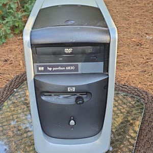 Puede incluir: Una torre de computadora de escritorio HP Pavilion 6830 en color plata y negro que cuenta con una unidad de DVD-ROM, una disquetera y un botón de encendido central. El panel frontal muestra el logo de HP y el nombre del modelo.
