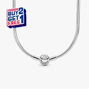 May include: A silver-colored necklace with a snake chain design. The necklace features a round clasp with the brand name engraved on it. A promotional sticker with the text "BUY 2 GET 1 FREE" is visible.