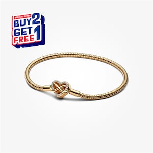 Könnte beinhalten: Ein goldfarbenes Armband mit herzförmigem Verschluss, das ein Unendlichkeitssymbol und kleine, klare Steine aufweist. Das Armband hat ein Schlangenketten-Design. Das Bild enthält auch ein Werbebanner "KAUFEN 2 BEKOMMEN 1 GRATIS".