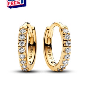 以下が含まれることがあります： クリアで輝く石が並んだ、ゴールドカラーのフープピアス2つ。ピアス内側には「ALE MET」の文字が刻印されています。左上には「BUY 2 GET 1 FREE」と書かれた青と赤のグラフィックがあります。