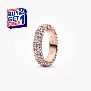 Puede incluir: Anillo de oro rosa con tres filas de piedras claras y brillantes. El anillo está grabado con "PANDORA ALE MET". Se muestra una oferta especial "COMPRA 2 Y LLÉVATE 1 GRATIS".