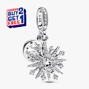 Puede incluir: Un charm de copo de nieve plateado con un centro en forma de estrella y detalles brillantes. Un charm redondo con el texto "THE FUTURE IS BRIGHT" está adjunto. El charm tiene un lazo para colgar. Una oferta "BUY 2 GET 1 FREE" está en la esquina superior izquierda.
