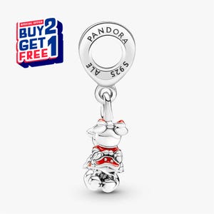 Puede incluir: Un charm de plata con dise&ntilde;o de Minnie Mouse, con detalles en rojo y blanco. El charm es de la marca Pandora. La imagen incluye una promoci&oacute;n de "COMPRA 2 Y LL&Eacute;VATE 1 GRATIS".