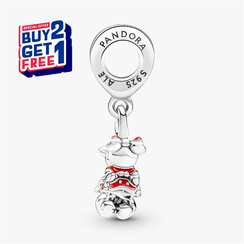 Puede incluir: Un charm de plata con dise&ntilde;o de Minnie Mouse, con detalles en rojo y blanco. El charm es de la marca Pandora. La imagen incluye una promoci&oacute;n de "COMPRA 2 Y LL&Eacute;VATE 1 GRATIS".