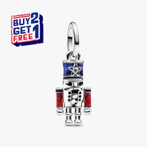 May include: A silver charm in the shape of a toy soldier, featuring a blue and red color scheme. The soldier has a blue hat with a star, red arms, and a detailed silver body. The charm is designed to hang from a bracelet or necklace.