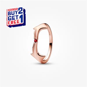 Puede incluir: Anillo de oro rosa con un diseño estilizado que presenta dos formas opuestas que se encuentran en una gema roja central. El anillo tiene la palabra "Pandora" grabada en el lateral. Una oferta de "Compra 2 y llévate 1 gratis" está en la esquina superior izquierda.