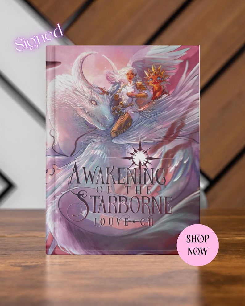 May include: A hardcover book titled "Awakening of the Starborne" with a fantasy illustration of a winged creature and a woman. The cover is predominantly purple and white, with the word "Signed" in the upper left corner.
