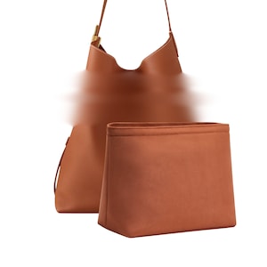 May include: A brown leather shoulder bag with a matching insert. The bag has a curved top and a long strap with a gold-colored buckle. The insert is rectangular and fits inside the bag.