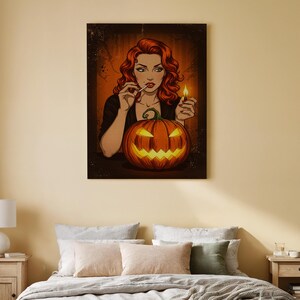 Puede incluir: Impresión en lienzo con temática de Halloween que representa a una mujer pelirroja sosteniendo un fósforo encendido y un cigarrillo, con una calabaza tallada frente a ella. La obra de arte tiene un estilo vintage de cómic con un borde oscuro y fondo naranja.