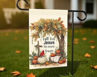 May include: A garden flag with a fall theme. The flag features a tree with autumn leaves, pumpkins, and the text "Fall for Jesus He never leaves." A red cardinal sits on a white pumpkin. The flag is displayed on a black metal stand.