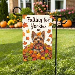 May include: A garden flag featuring a Yorkshire Terrier dog surrounded by colorful autumn leaves. The flag reads "Falling for Yorkies" in a decorative font. The dog wears a scarf and is surrounded by red, orange, and green leaves.