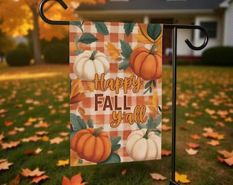 Könnte beinhalten: Eine Gartenflagge mit Herbstthema. Die Flagge zeigt orange und weiße Kürbisse, Herbstblätter und den Text "Happy Fall y'all" auf kariertem Hintergrund. Die Flagge wird auf einem schwarzen Metallständer im Garten gezeigt.