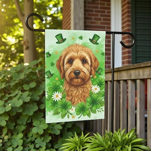 May include: A garden flag featuring a golden doodle dog surrounded by shamrocks, green top hats, and white daisies on a light green background. The flag is hanging on a black metal stand, perfect for St. Patrick's Day.