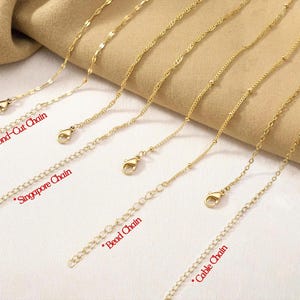 Pu&ograve; includere: Una collezione di quattro catenine in metallo color oro, ciascuna dotata di chiusura a moschettone e catenella di estensione. Gli stili sono etichettati come Diamond-Cut Chain, Singapore Chain, Bead Chain e Cable Chain, disposti in parallelo.