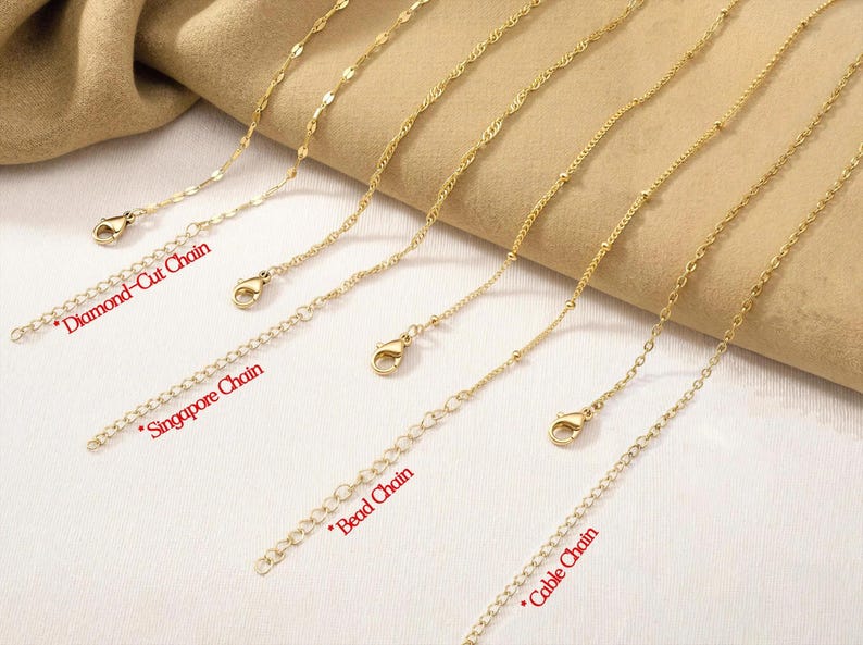 Pu&ograve; includere: Una collezione di quattro catenine in metallo color oro, ciascuna dotata di chiusura a moschettone e catenella di estensione. Gli stili sono etichettati come Diamond-Cut Chain, Singapore Chain, Bead Chain e Cable Chain, disposti in parallelo.