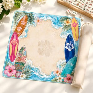 May include: A square mat featuring a central sandy beach design with a large hibiscus flower watermark. The border displays blue ocean waves, green palm leaves, colorful hibiscus flowers, and six surfboards in shades of brown, pink, blue, and yellow.