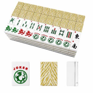 May include: A set of white Mahjong tiles featuring green and red ink designs, including dragons, numbers, and Joker labels. The backs of the tiles display a gold and white tiger stripe pattern. Three individual tiles are shown below the main stack.