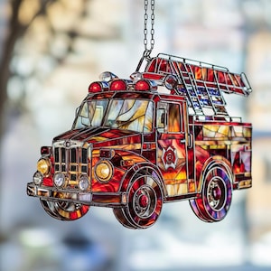 Puede incluir: Adorno de camión de bomberos de vidrieras con una escalera, luces y un emblema de los bomberos. El camión presenta vidrio rojo, naranja y amarillo con un marco de metal negro. El adorno cuelga de una cadena plateada.