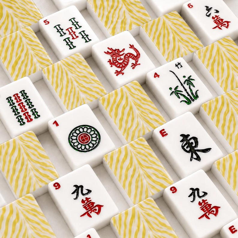 May include: A collection of Mahjong tiles featuring white faces with various red, green, and black symbols, including a red dragon, bamboo, and numerical characters. The backs of the tiles display a textured yellow and white tiger stripe pattern.