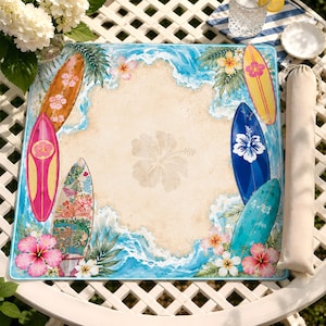 May include: A square beach-themed mat featuring a central sandy area with a faint hibiscus flower print, surrounded by blue ocean waves, green palm leaves, colorful surfboards, and vibrant pink and white hibiscus flowers at the corners.