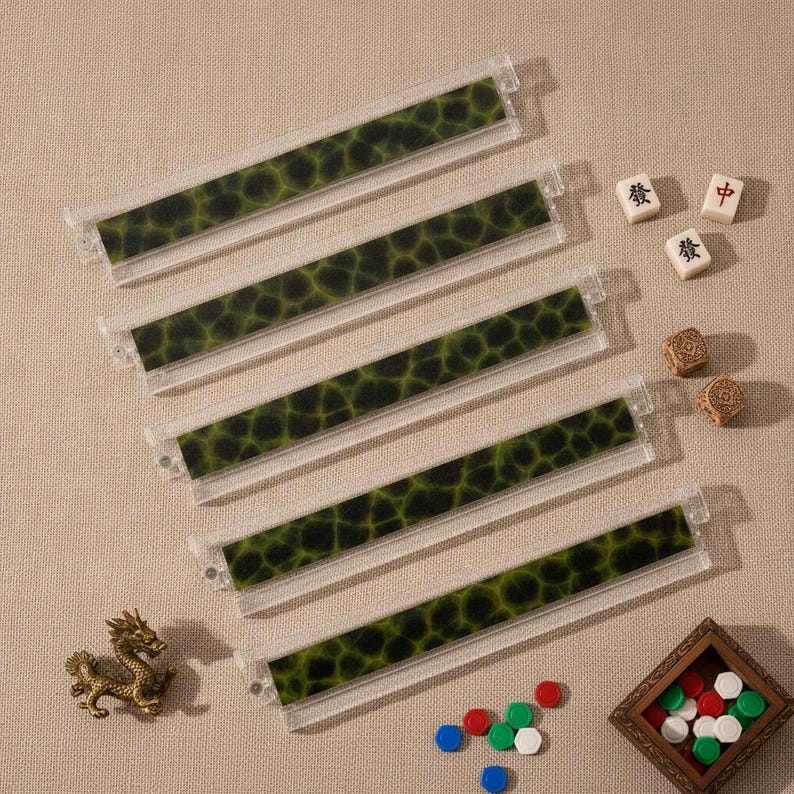 May include: Five clear acrylic mahjong tile racks featuring a dark green and black mottled pattern. The set includes three small white mahjong tiles with black and red characters, two brown textured dice, a gold dragon figurine, and small tokens.