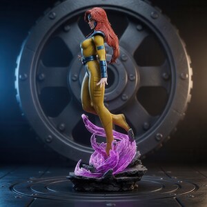 May include: A collectible figurine of a character with long red hair, wearing a yellow bodysuit with dark blue accents, including a belt, shoulder pads, and arm guards. The figure stands atop a base of translucent purple energy and dark rocks.