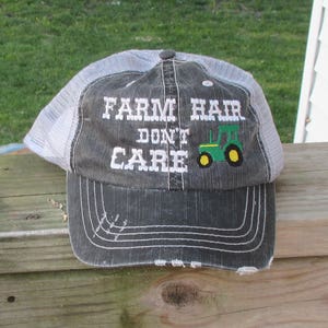 May include: A gray and white trucker hat with the text "FARM HAIR DON'T CARE" and a green and yellow tractor graphic.