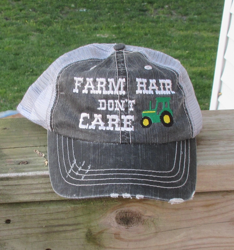 May include: A gray and white trucker hat with the text "FARM HAIR DON'T CARE" and a green and yellow tractor graphic.