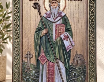 May include: A rectangular wall plaque featuring a relief carving of Saint Patrick in green and white robes, holding a staff and a book. The figure is framed by an ornate border with Celtic knotwork, with the text Saint Patrick at the top.