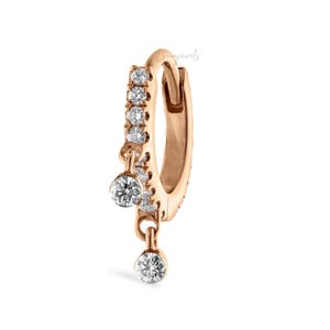 May include: Rose gold hoop earring with a row of small, clear stones and two dangling, round, clear stones. The earring is shown against a white background. The word "Loomjewels" is written in cursive on the top right.