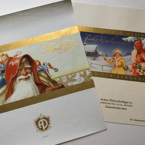 May include: Two vintage Christmas chocolate boxes. One features Santa Claus with the text "Frohe Fest" in gold lettering. The other box has a winter scene with the text "Frohe Weihnachten" and Santa Claus.