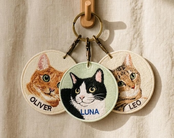 May include: Three embroidered cat keychains with different cat faces. One is orange with the name "OLIVER", one is black and white with the name "LUNA", and one is tabby with the name "LEO". The keychains are attached to a metal ring.