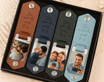 May include: A set of four leather bookmarks in a black box. Each bookmark is a different color: brown, navy, green, and light blue. Each bookmark has a photo and the text "You mean the world to us."