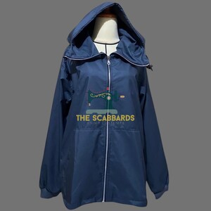 Op de afbeelding: Een marineblauwe jas met capuchon en een lange ritssluiting. De jas heeft een trekkoord aan de capuchon en een logo met de tekst "THE SCABBARDS ANIME COSTUMES". De jas wordt op een mannequin getoond.