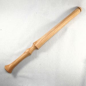 May include: A light-colored wooden rolling pin with a turned handle and a cylindrical rolling surface. The handle has a decorative, carved design. The rolling pin is made of a light-colored wood, possibly maple or ash.