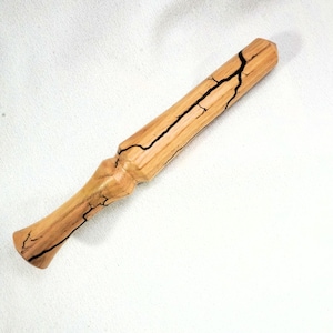 May include: A handcrafted wooden wand with a light brown finish and dark, crack-like markings. The wand has a flared handle and a tapered body, with a faceted tip. The wood grain is visible, adding to its natural aesthetic.
