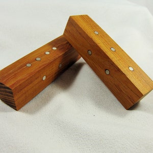 Könnte beinhalten: Zwei Holzblöcke mit silbernen Punkten auf jeder Seite. Die Blöcke sind in V-Form angeordnet.