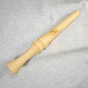 May include: A light-colored wooden tool with a flared base and a rounded top. The tool has a cylindrical body with a decorative ring near the center. The wood grain is visible, and the tool appears to be handmade.