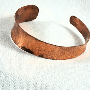 May include: A wide copper bracelet with a hammered finish. The bracelet is simple and elegant.