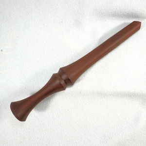 May include: A handcrafted, reddish-brown wooden wand. The wand features a flared handle, a decorative midsection, and a long, tapered shaft. The wood grain is visible, giving the wand a natural, rustic appearance. The wand is approximately 12 inches long.