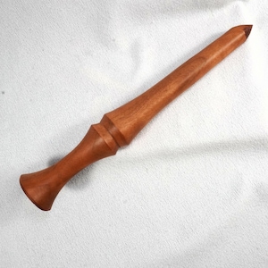 May include: A handcrafted wooden wand with a rich, reddish-brown hue. The wand features a flared handle, a detailed midsection, and a tapered tip. The wand is approximately 12 inches long, perfect for cosplay or display.
