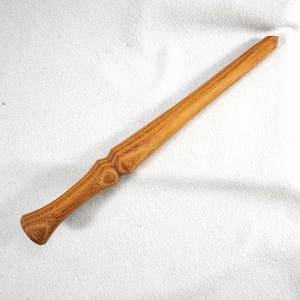 May include: A handcrafted wooden wand with a light brown finish. The wand features a detailed handle with a textured design and a tapered body. The wand is approximately 12 inches long, perfect for cosplay or display.