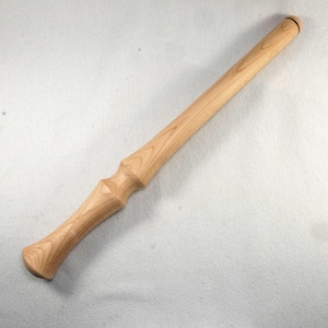 May include: A light-colored wooden wand with a rounded handle and a decorative, hourglass-shaped midsection. The wand is approximately 14 inches long and has a smooth, polished finish, showcasing the natural wood grain.